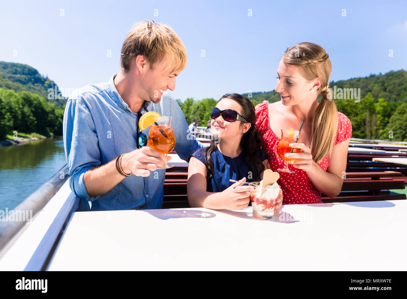 La famiglia a pranzo sulla crociera fluviale con bicchieri da birra sul ponte Foto Stock