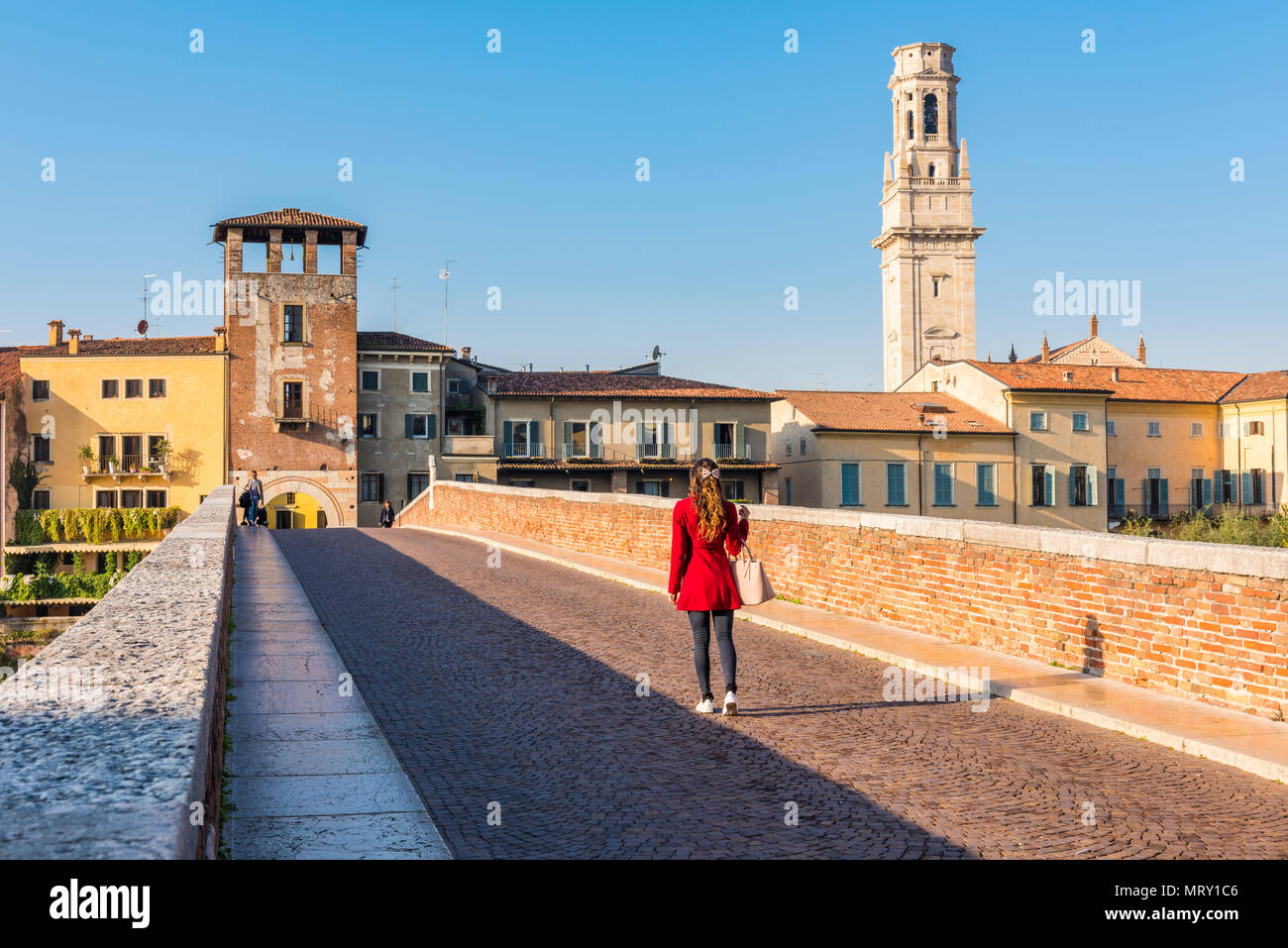 Donna che cammina lungo il Ponte Pietra (ponte di pietra). Verona, Veneto, Italia Foto Stock
