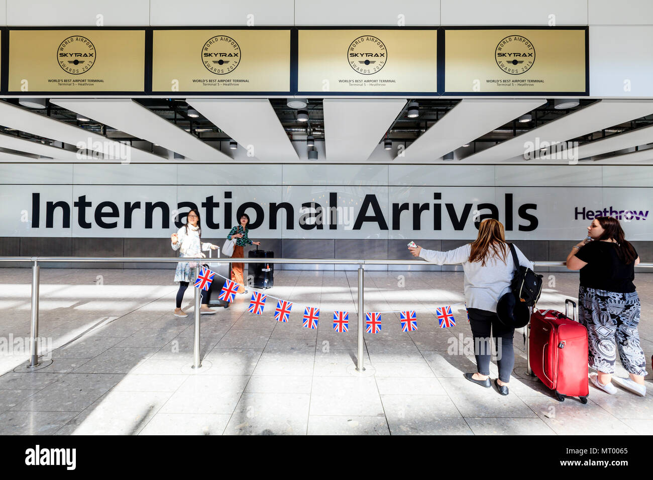 Persone in attesa presso il terminale 5 International Hall Arrivi all'aeroporto di Heathrow di Londra, Regno Unito Foto Stock