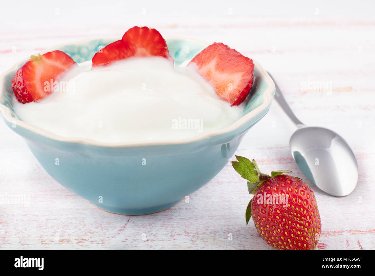 Fresche succose fragole con yogurt biologici in ceramica blu ciotola sul tavolo di legno, fuoco selettivo Foto Stock