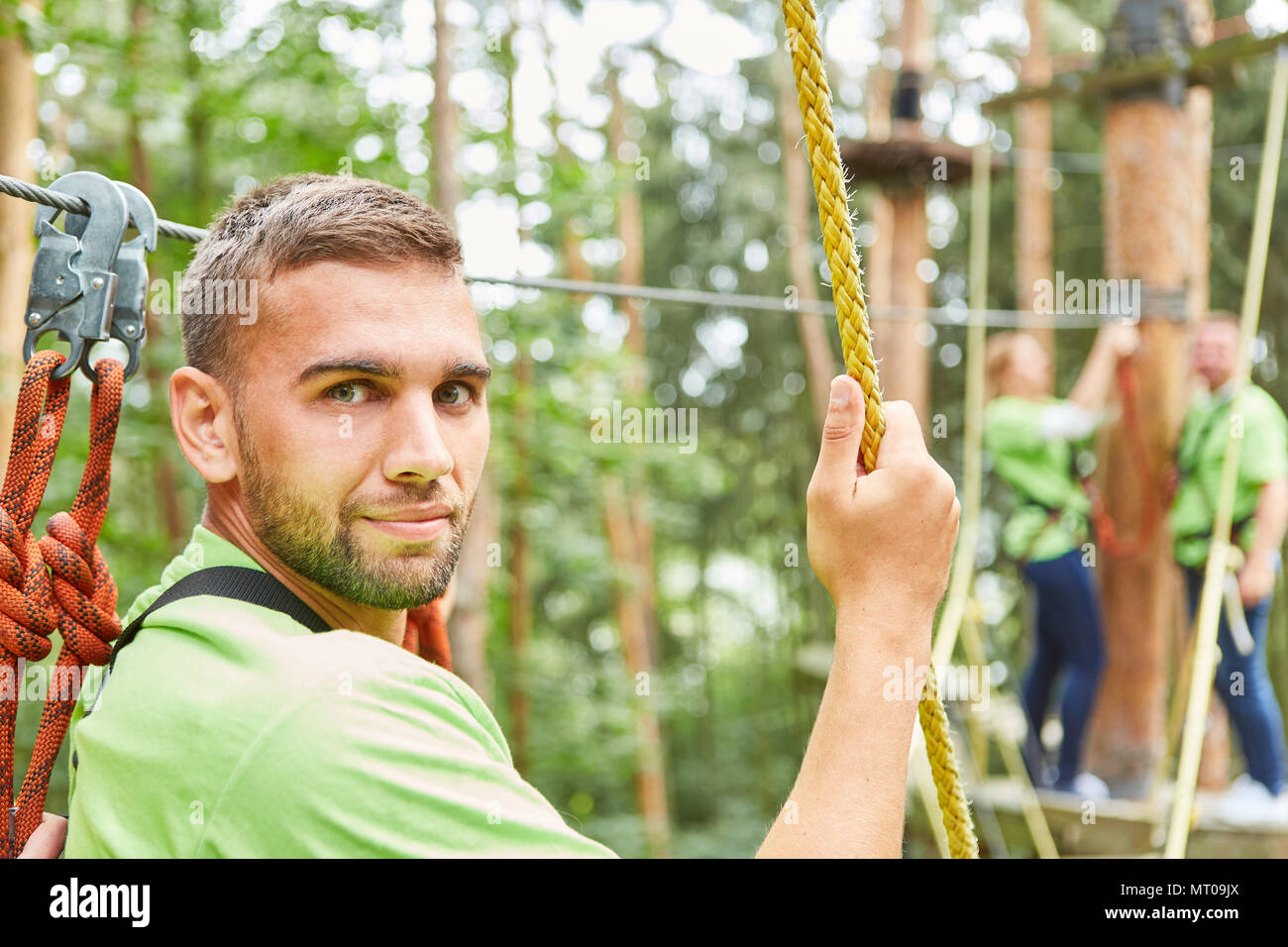 Giovane uomo in filo alto giardino come un principiante in un corso di arrampicata appare incerto ed ansioso Foto Stock