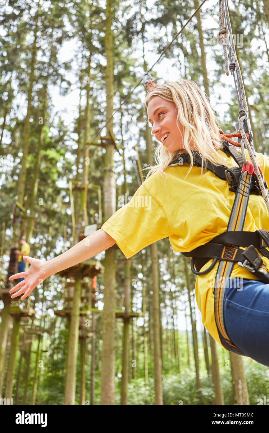 Giovane donna nella foresta di arrampicata o corde alte corso mentre rappelling su un corso di arrampicata Foto Stock