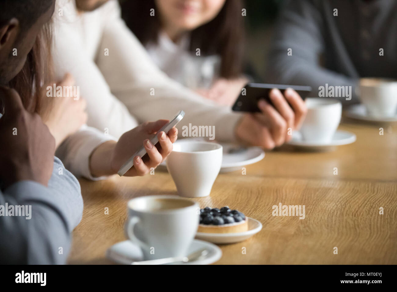 Diverse persone che utilizzano smartphone alla tabella cafe, vista ravvicinata Foto Stock