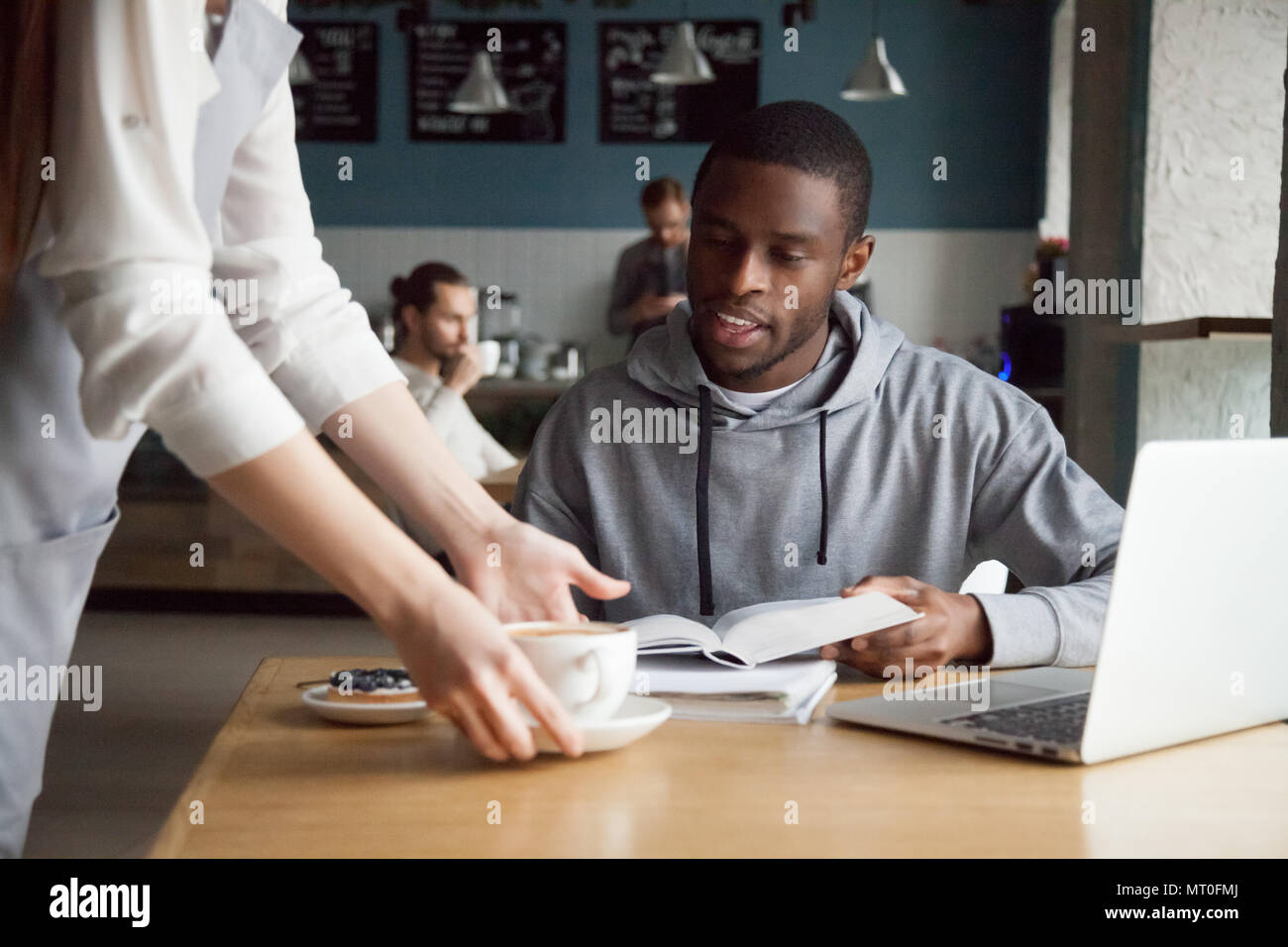 La cameriera che serve caffè e sorridente afro-americano il cliente Foto Stock