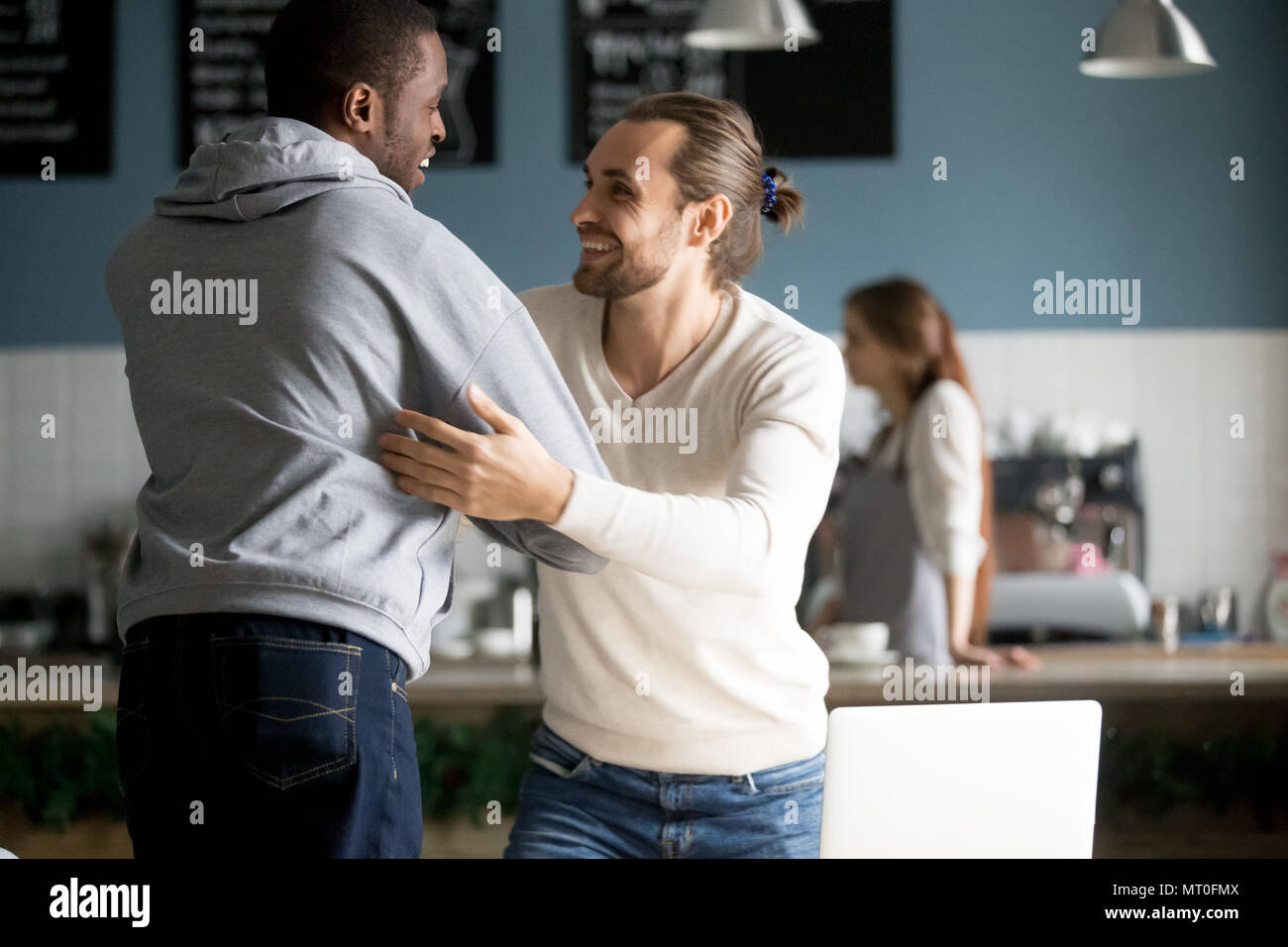 Sorridente diversi amici maschi abbracciando saluto alla riunione in ca Foto Stock