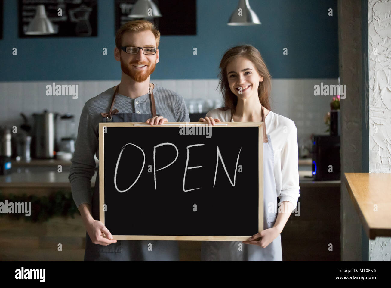 Sorridente cameriere e cameriera holding lavagna con Open Firmare, p Foto Stock