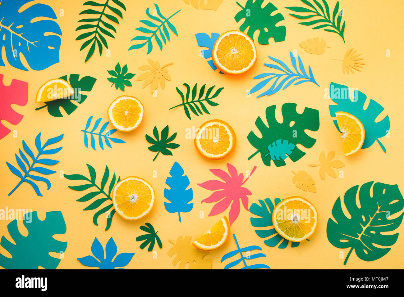 Intestazione tropicale con le arance, foglie e frutti pattern su un giallo brillante background. Estivo soleggiato appartamento colorato laici carta con ritagli. Foto Stock
