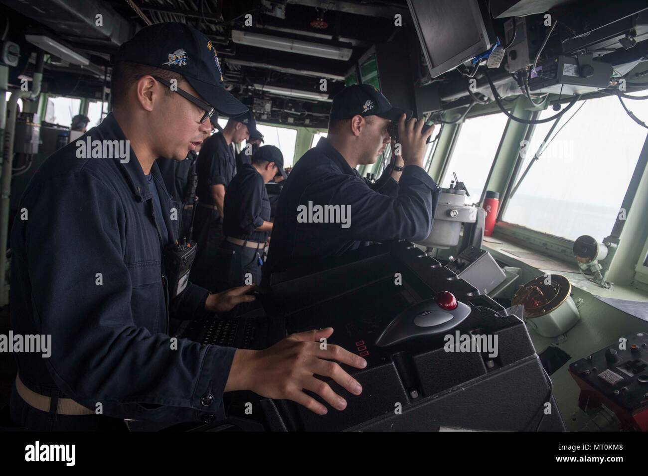 Sul mare del sud della Cina (13 luglio 2017) Ensign Terence Viernes, sinistra, comunica la posizione dei contatti di superficie al pubblico ufficiale di coperta a bordo del Arleigh Burke-class guidato-missile destroyer USS Stethem (DDG 63) durante un transito verso Singapore. Stethem è di pattuglia il supporto di sicurezza e stabilità nella Indo-Asia-regione del Pacifico. (U.S. Foto di Marina di Massa lo specialista di comunicazione 2a classe Ryan Harper/ rilasciato) Foto Stock