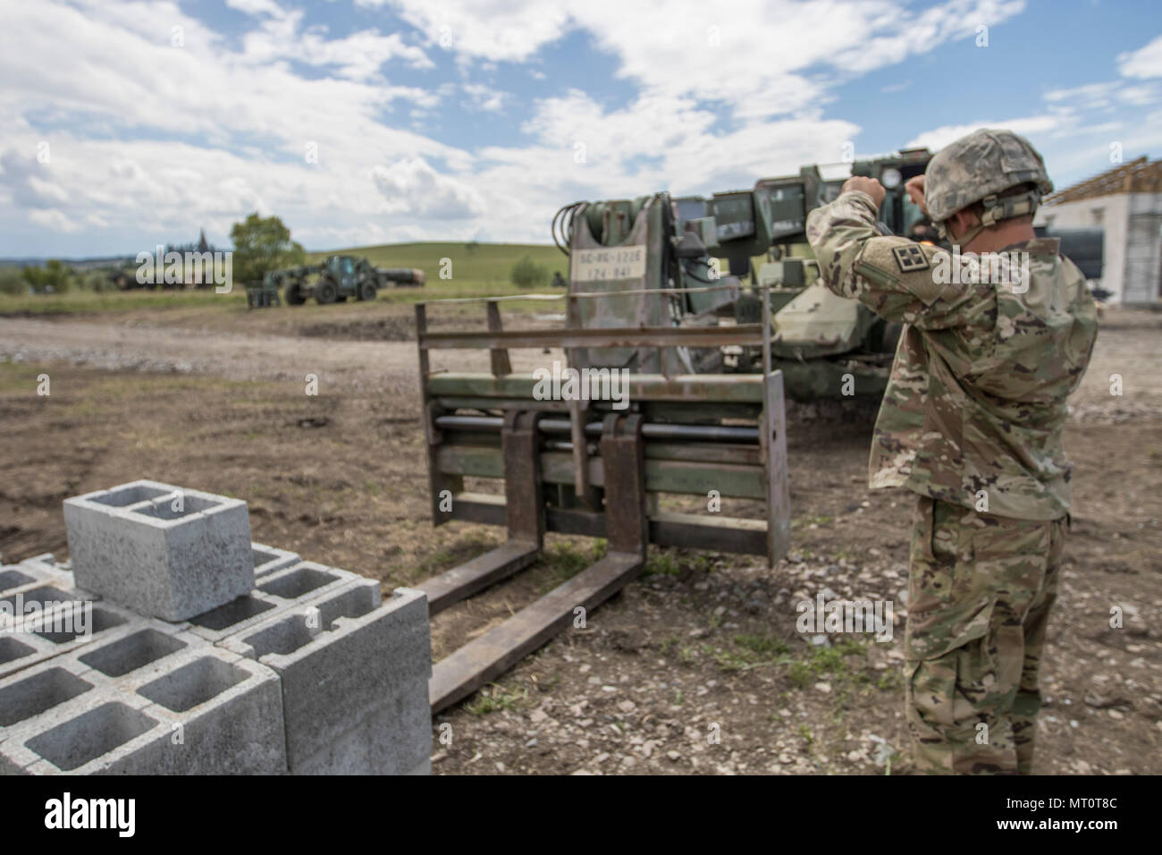 Stati Uniti La riserva di esercito soldato, Sgt. Byron Haynes, ingegnere 733rd Company, Greenville, S.C. guide un U.S. La riserva di esercito soldato, con segnali a mano, per spostare un pallet di blocchi di calcestruzzo di scorie durante la risoluta Castello 17 a Cincu, Romania, 15 luglio, 2017. Haynes, chi è un'autostrada inspector, in Carolina del Sud, si è recato in Romania con la sua società per aiutare a completare la costruzione di un nuovo centro di formazione che fornisce le forze alleate hanno la possibilità di prepararsi per il potenziale conflitto. L'intera operazione è guidato dalle leggi degli Stati Uniti La riserva di esercito di ingegneri, chi ha spostato i soldati e le attrezzature da parte degli Stati Uniti alla Romania per un periodo Foto Stock