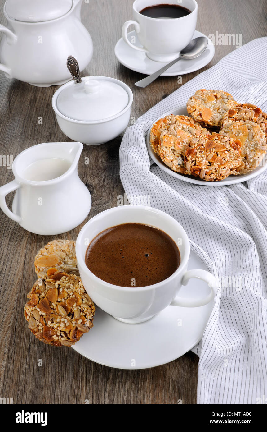 Una tazza di caffè con senza glutine cookies da cereali sul tavolo da caffè. Si tratta di tempo hanno un morso Foto Stock