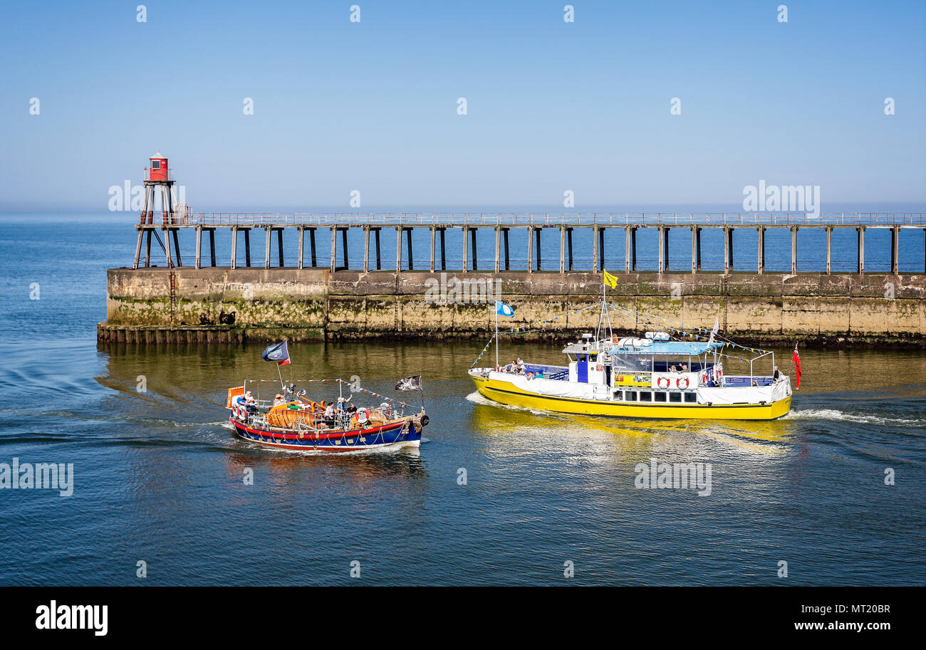 Le imbarcazioni turistiche attraversando davanti a Whitby Oriente pier beacon prese a Whitby, nello Yorkshire, Regno Unito il 21 maggio 2018 Foto Stock