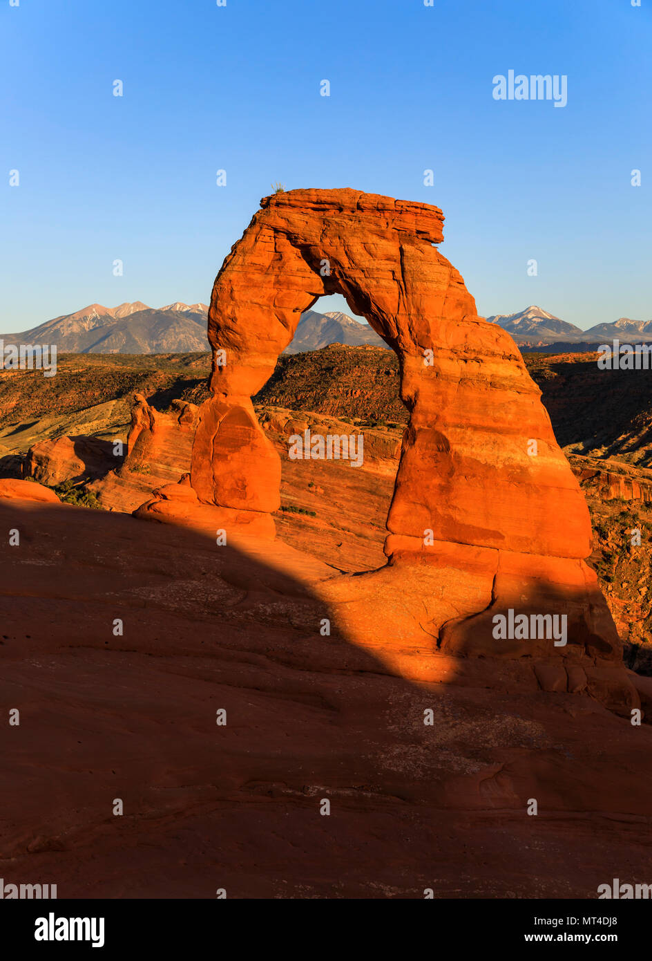 In questa vista in verticale le ombre fino al creep su Delicate Arch nel sole di setting del Parco Nazionale di Arches, Utah, Stati Uniti d'America. Questo spettacolare parco nazionale è Foto Stock