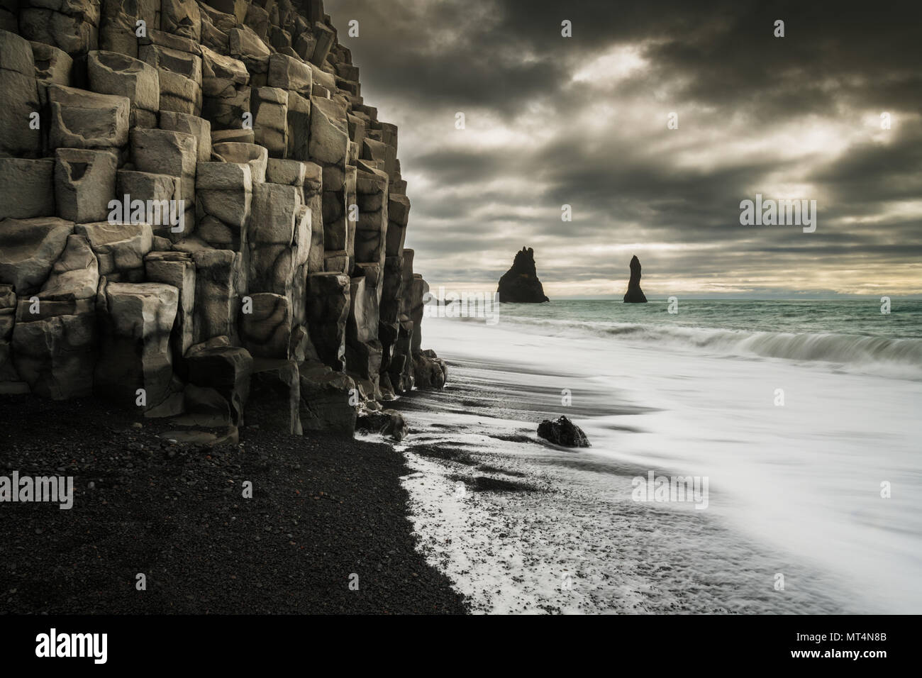 Reynisfjara famosa spiaggia nera con le colonne di basalto e il mare Reynisdrangar pile. Foto Stock