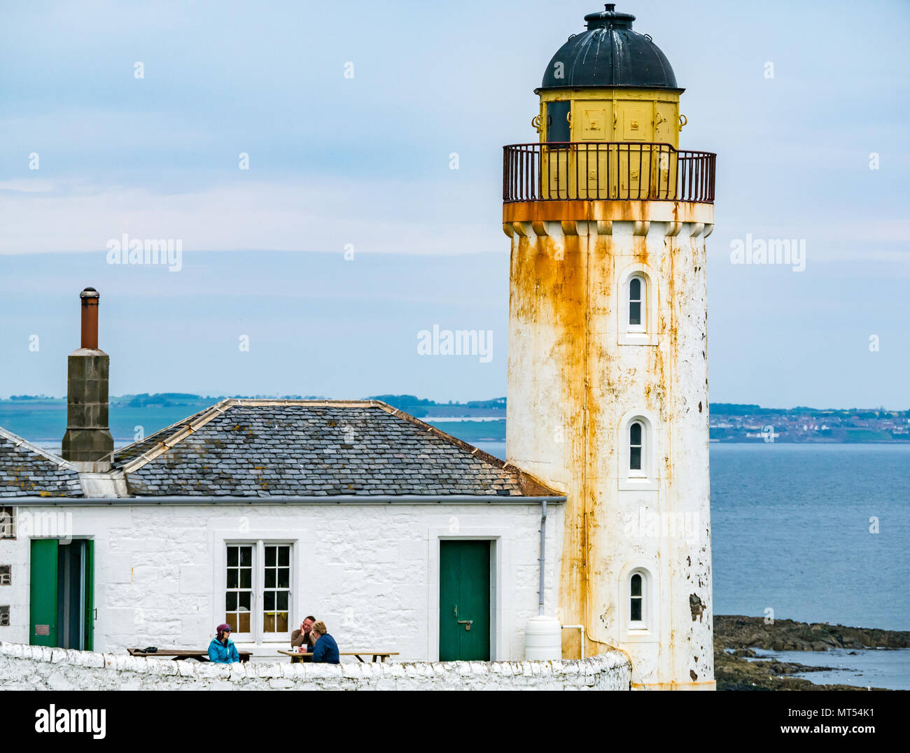 Le persone al tavolo da picnic con tazze, bassa luce faro osservatorio ornitologico, Isola di maggio, Firth of Forth, Scotland, Regno Unito Foto Stock