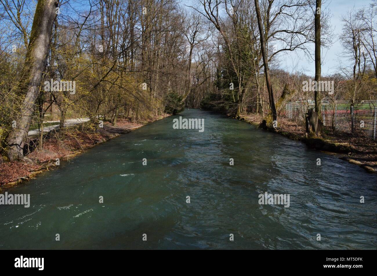 Ampio fiume azzurro che scorre attraverso un parco durante la primavera a Monaco di Baviera in Germania Foto Stock