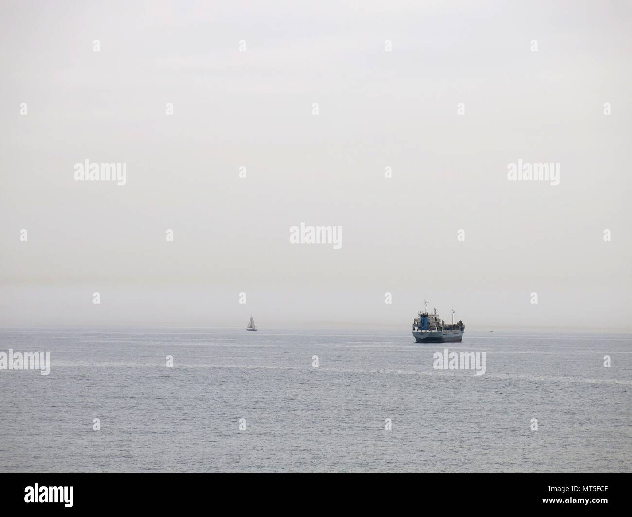 Freighter e barca a vela all'orizzonte. Concetto : minimalismo in fotografia. Foto Stock