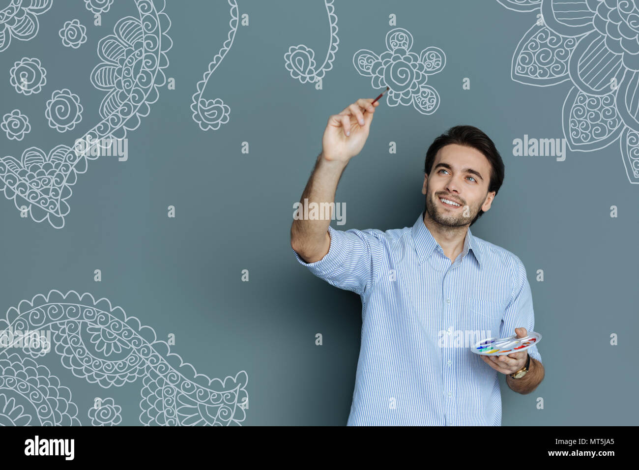 Pittore di talento sorridente durante il disegno di un fiore Foto Stock