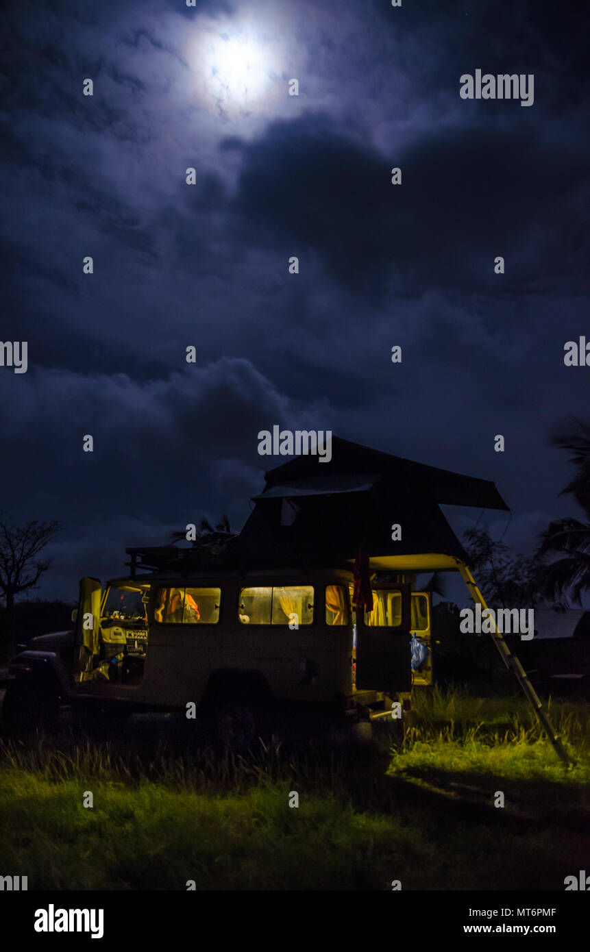 4x4 offroad veicolo con tetto tenda e luce interiore durante la notte con cielo nuvoloso e forte luna, concetto di campeggio Foto Stock