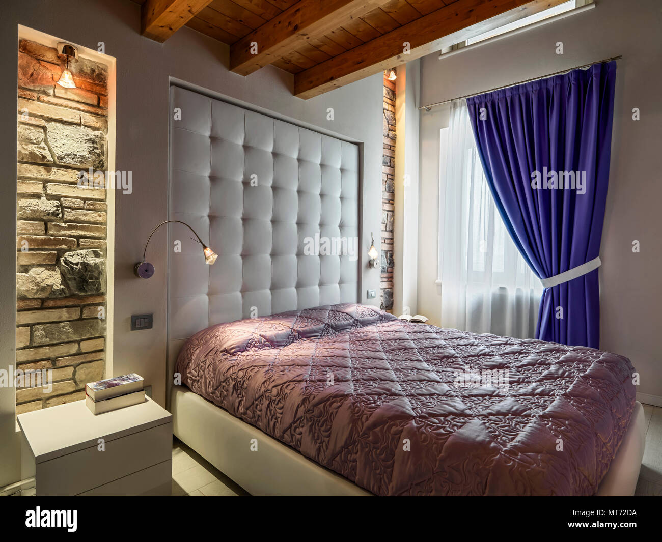 Contemporanee camere da letto interno con soffitto in legno e tende blu, una parte di parete sono in pietra Foto Stock