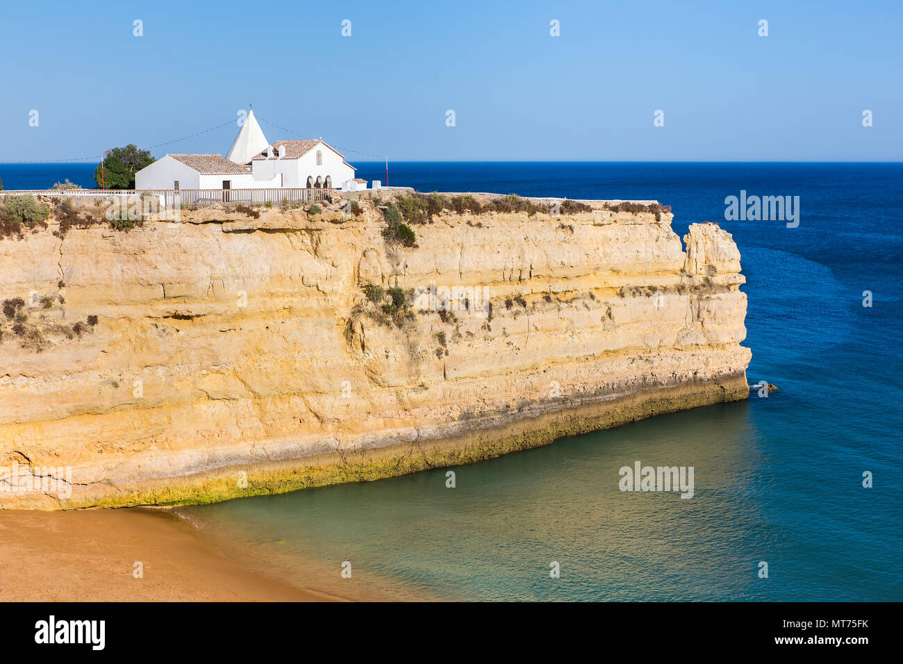 Di piccole dimensioni e di colore bianco chiesa portoghese sulla roccia ripida nel blu del mare Foto Stock