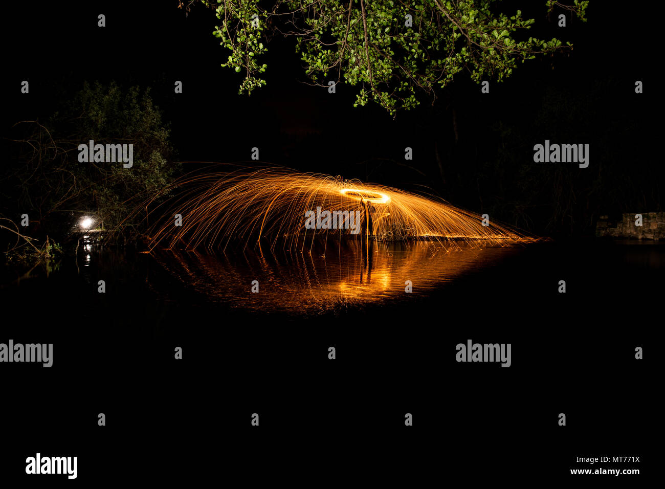 Una lunga esposizione con scintille di lana di acciaio su un flusso di acqua e di riflessioni Foto Stock