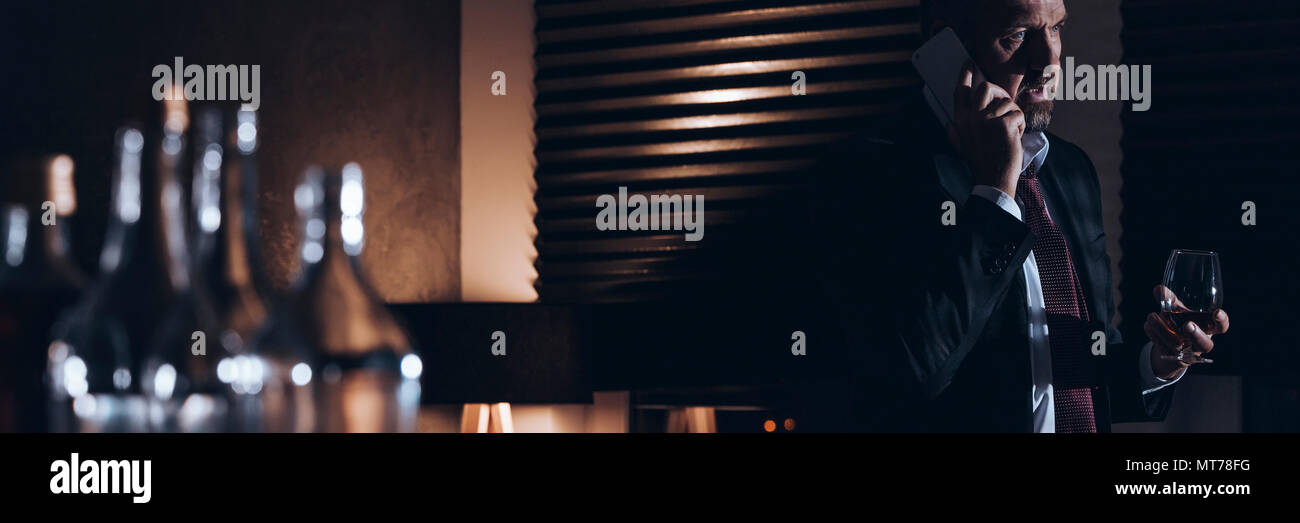 Panorama di un lavoro di bere il brandy e parlando al telefono Foto Stock