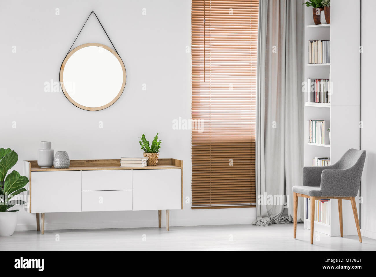 Round specchio appeso sul muro bianco al di sopra di un armadio in una luminosa camera Contemporary interior. Foto reale. Foto Stock