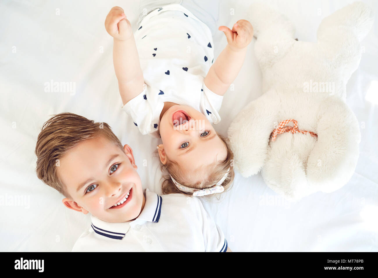 Bambini positivo sorridente giacente su un letto bianco. Foto Stock