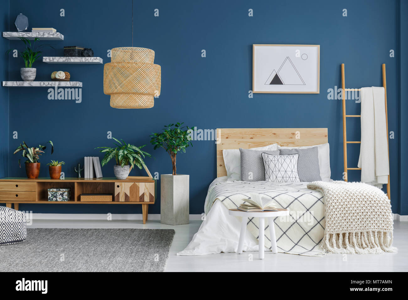 Accogliente interiore camera da letto con un letto matrimoniale e armadio in legno, lampadario e parete blu Foto Stock