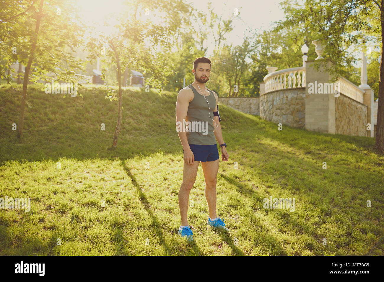 Un runner guy sorge nel parco al tramonto. Foto Stock