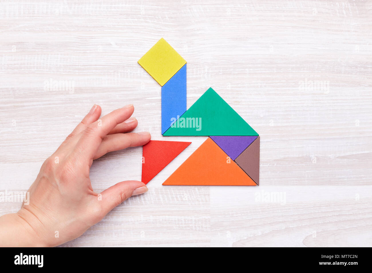 Da sopra il colpo di persona la composizione di tangram figure in forma di casa su un tavolo di legno. Foto Stock