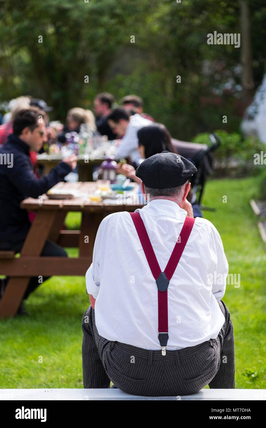 La vista posteriore di un uomo che indossa le bretelle e un cappuccio di  relax al sole Foto stock - Alamy