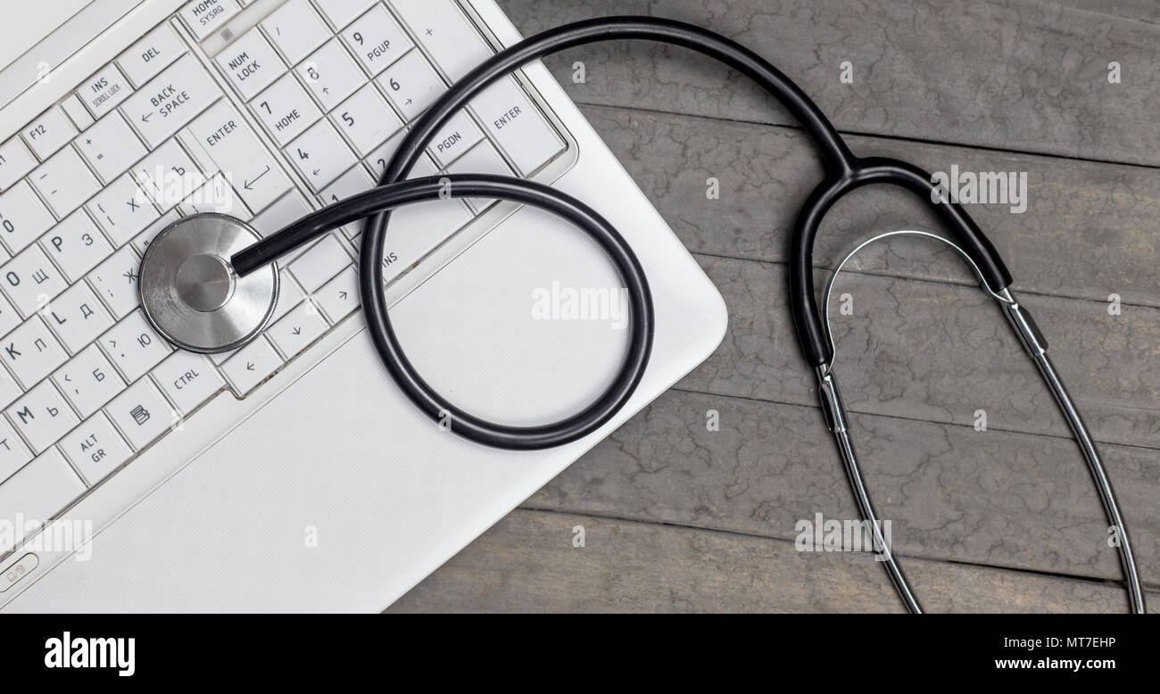 Vista dall'alto di uno stetoscopio a registrare le informazioni della carta e del laptop. Foto Stock