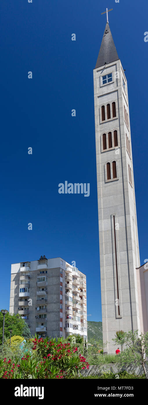 A Mostar (Bosnia Erzegovina), un blocco di appartamenti dominato dal nuovo campanile di San Pietro e Paolo chiesa francescana (350.96 piedi alto). Foto Stock