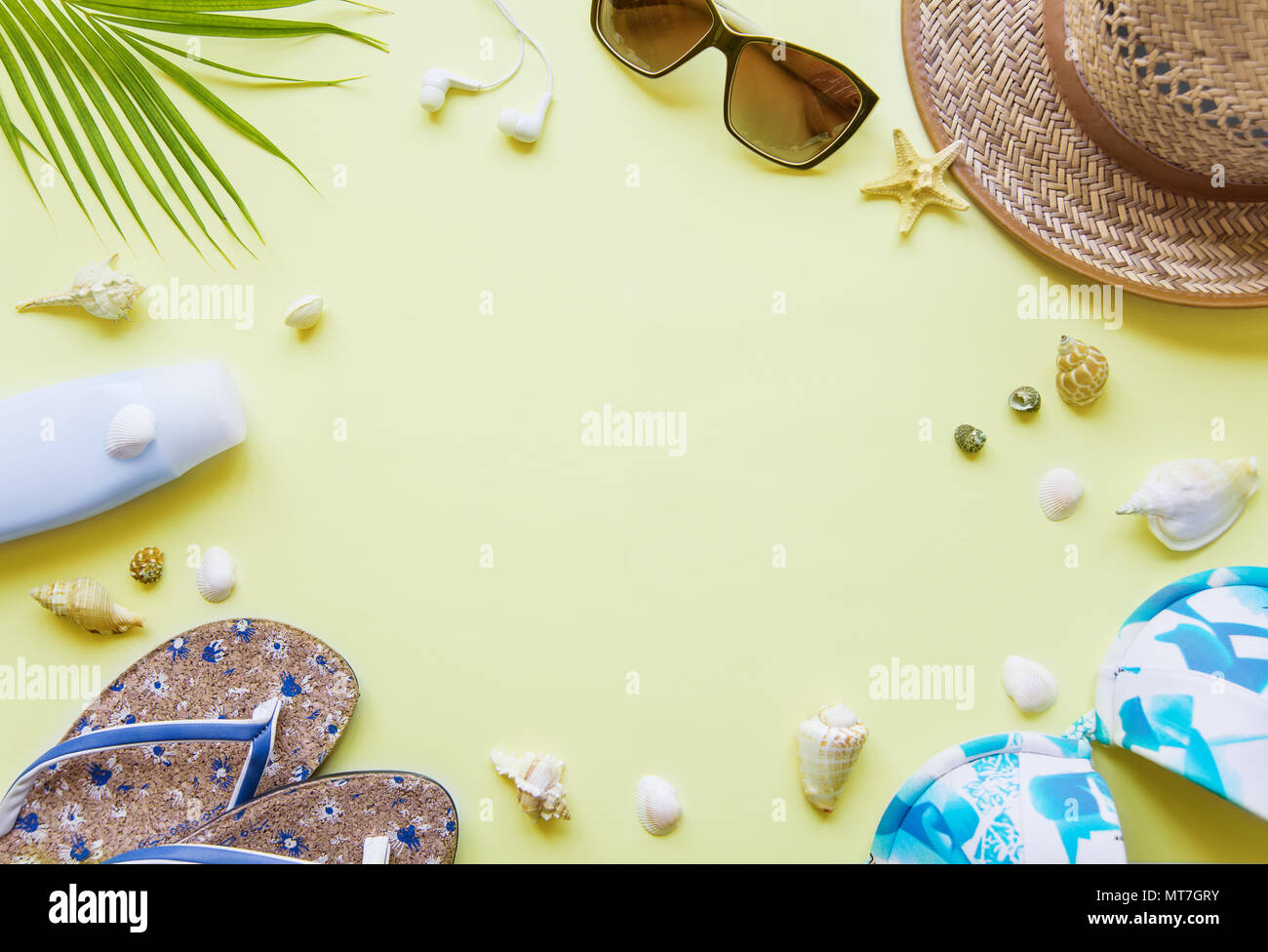 Traveler accessori: verde tropicale di foglie di palma, flip-flop, costume da bagno, conchiglie e gli occhiali da sole sono su sfondo giallo con copy-spazio. Vista superiore trav Foto Stock