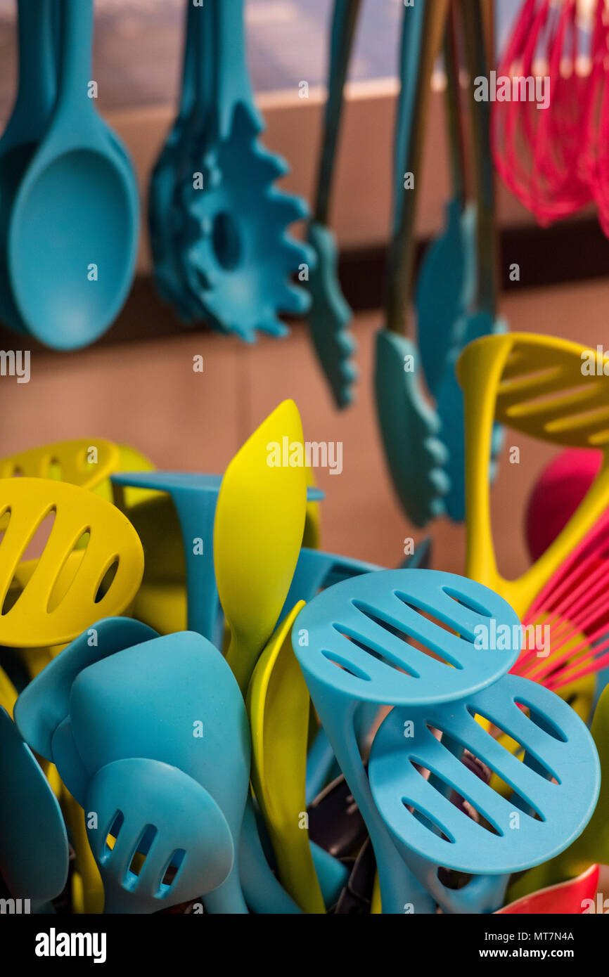 Una selezione delle colorate in plastica o gomma utensili da cucina sul visualizzatore in corrispondenza di una cucina di cottura o negozio di vendita di attrezzature da cucina e gadget. Foto Stock