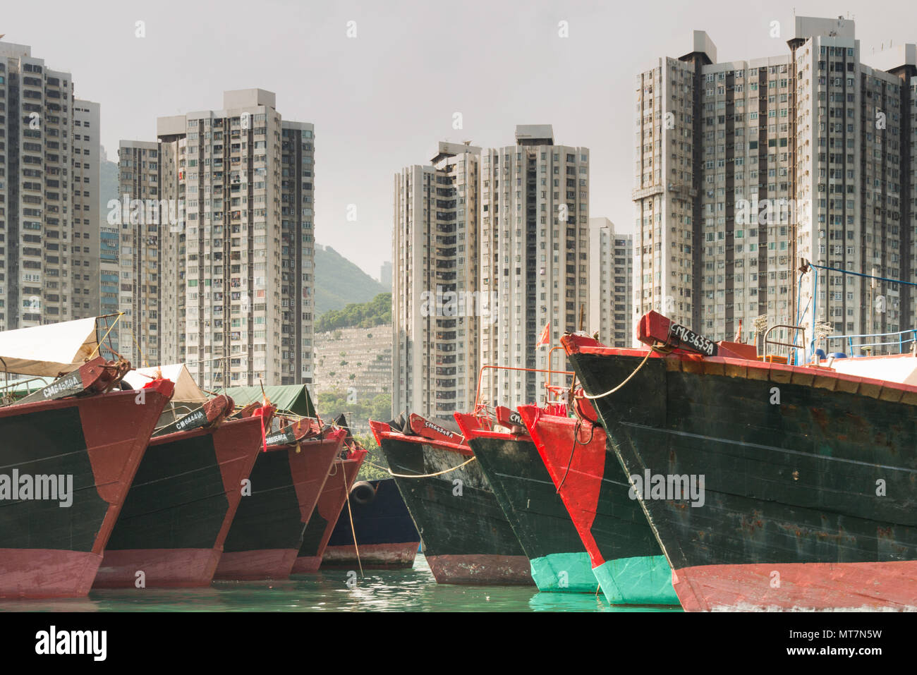 Commerciale barche da pesca al di ancoraggio con elevato aumento appartamenti in background in Hong Kong Foto Stock