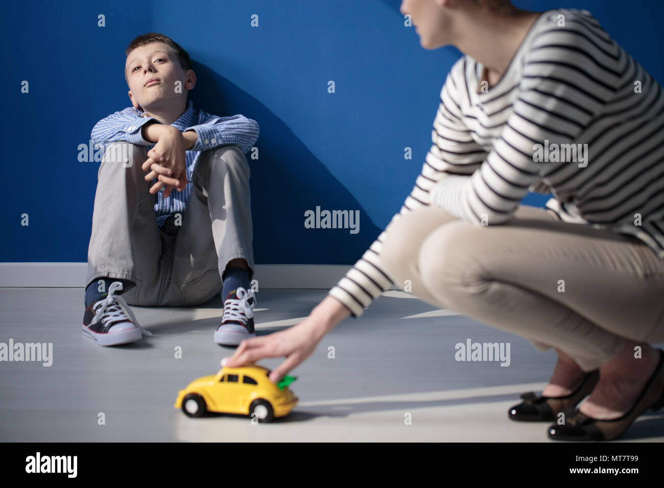 Mom giocando con il figlio autistico seduto su un pavimento Foto Stock
