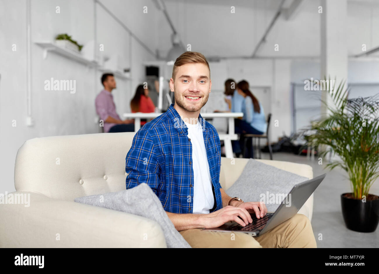 Uomo sorridente con notebook lavorando in ufficio Foto Stock