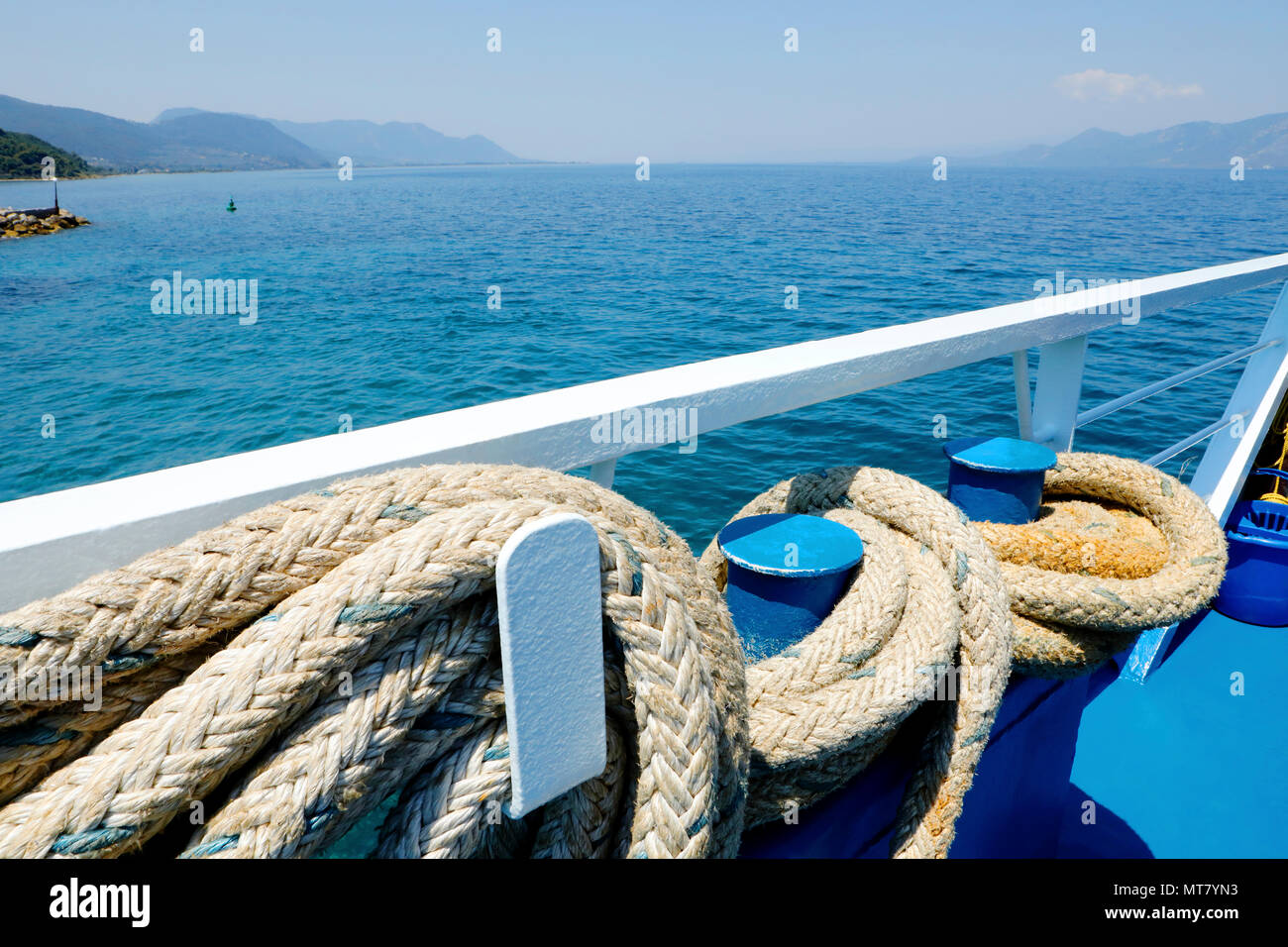 Viaggiare per mare. Vicino la fune di ancoraggio in corrispondenza di ferry boat deck e bellissima vista del mare con le montagne sullo sfondo a giornata di sole. Foto Stock