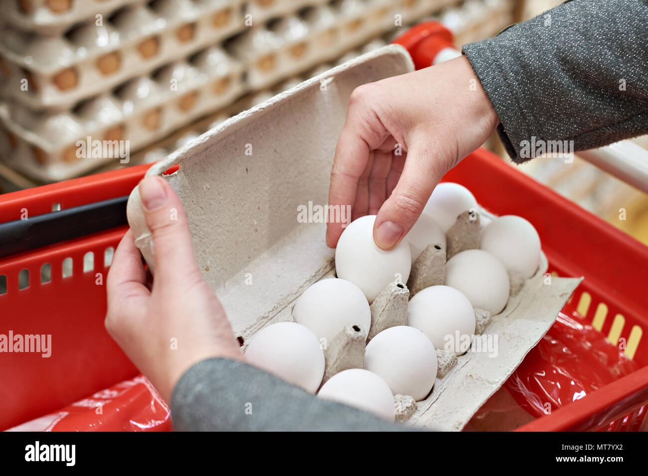 Le mani della donna con confezioni di uova di colore bianco in negozio Foto Stock