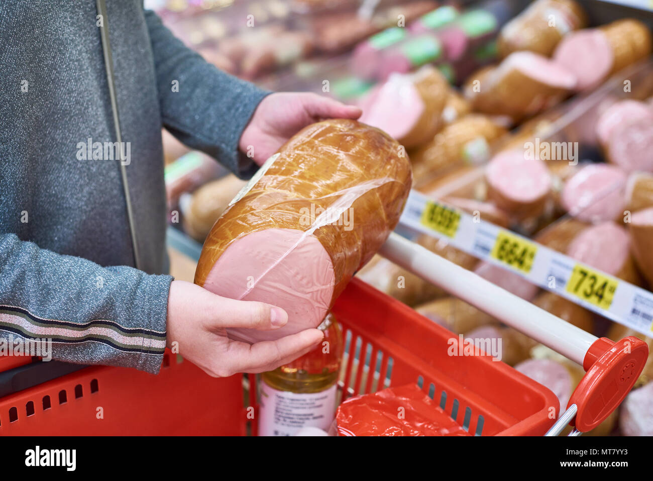 Acquirente con salsiccia con un paniere di generi alimentari in negozio Foto Stock