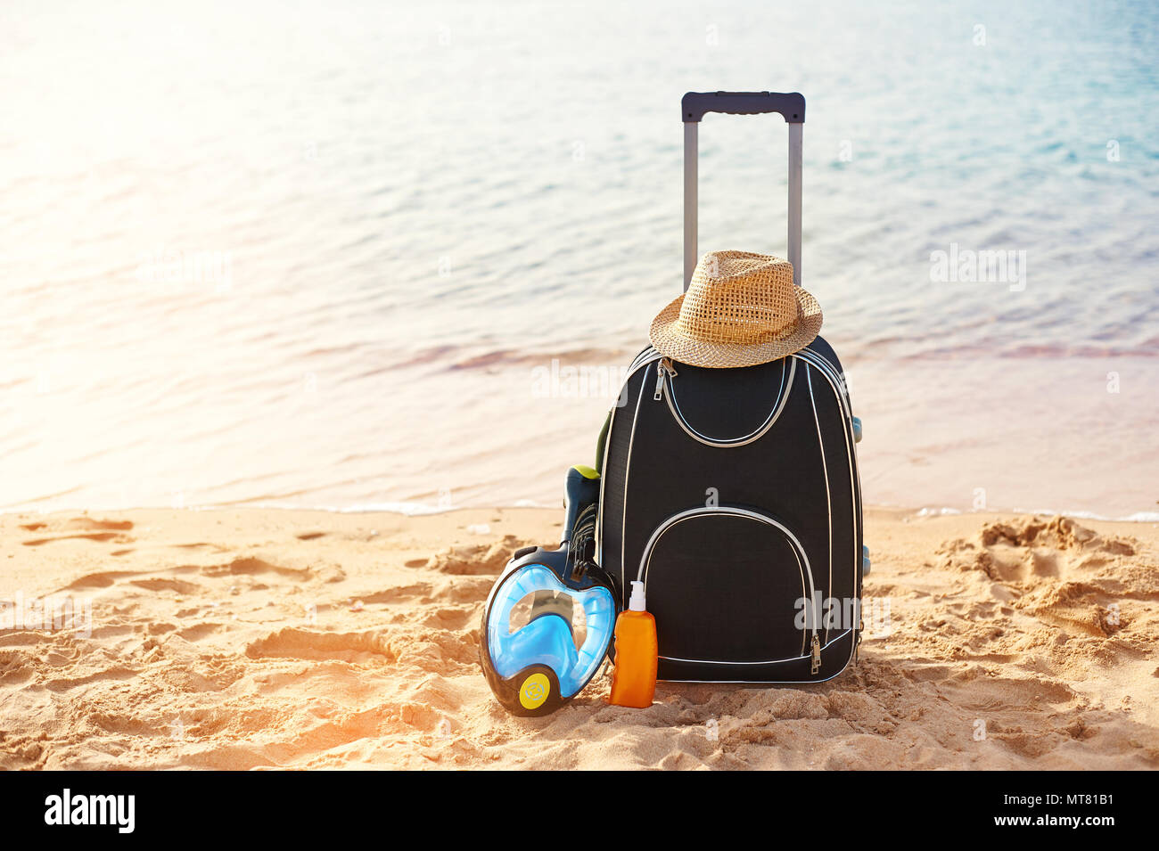 Valigia e cappello, crema solare con una maschera. Il mare tropicale, spiaggia in background. Il concetto di ricreazione di estate viaggi e traffico crocieristico Foto Stock