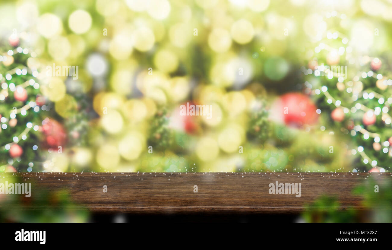 Svuotare legno marrone scuro tavolo con abstract blur albero di Natale decorazioni in rosso la sfera e la caduta di neve con sfondo bokeh luce,vacanze inverno sfondo,Moc Foto Stock