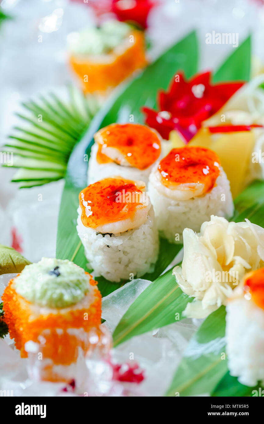 Un sacco di sushi rotoli con vari ripieni. Colpo di cotto giapponese classico cibo servito su ghiaccio. Immagine di sfondo Foto Stock