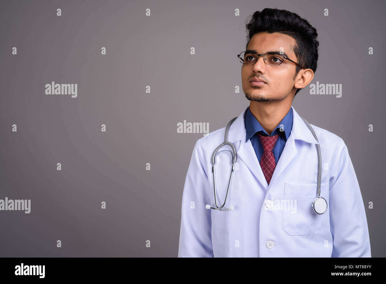 Giovane uomo indiano medico contro uno sfondo grigio Foto Stock