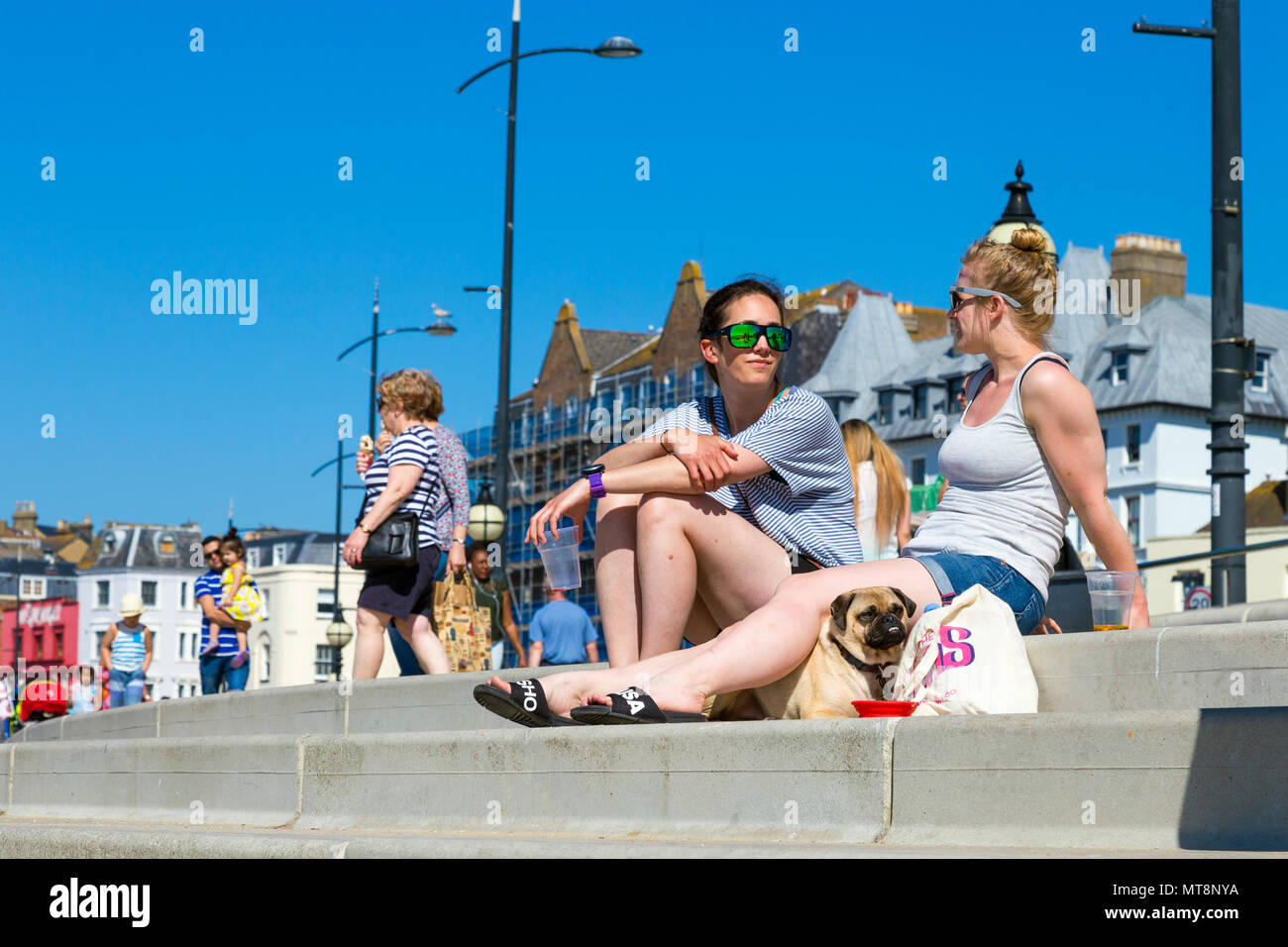 Due donne e un cane seduto di fronte spiaggia in Margate e parlare, Margate, Regno Unito Foto Stock