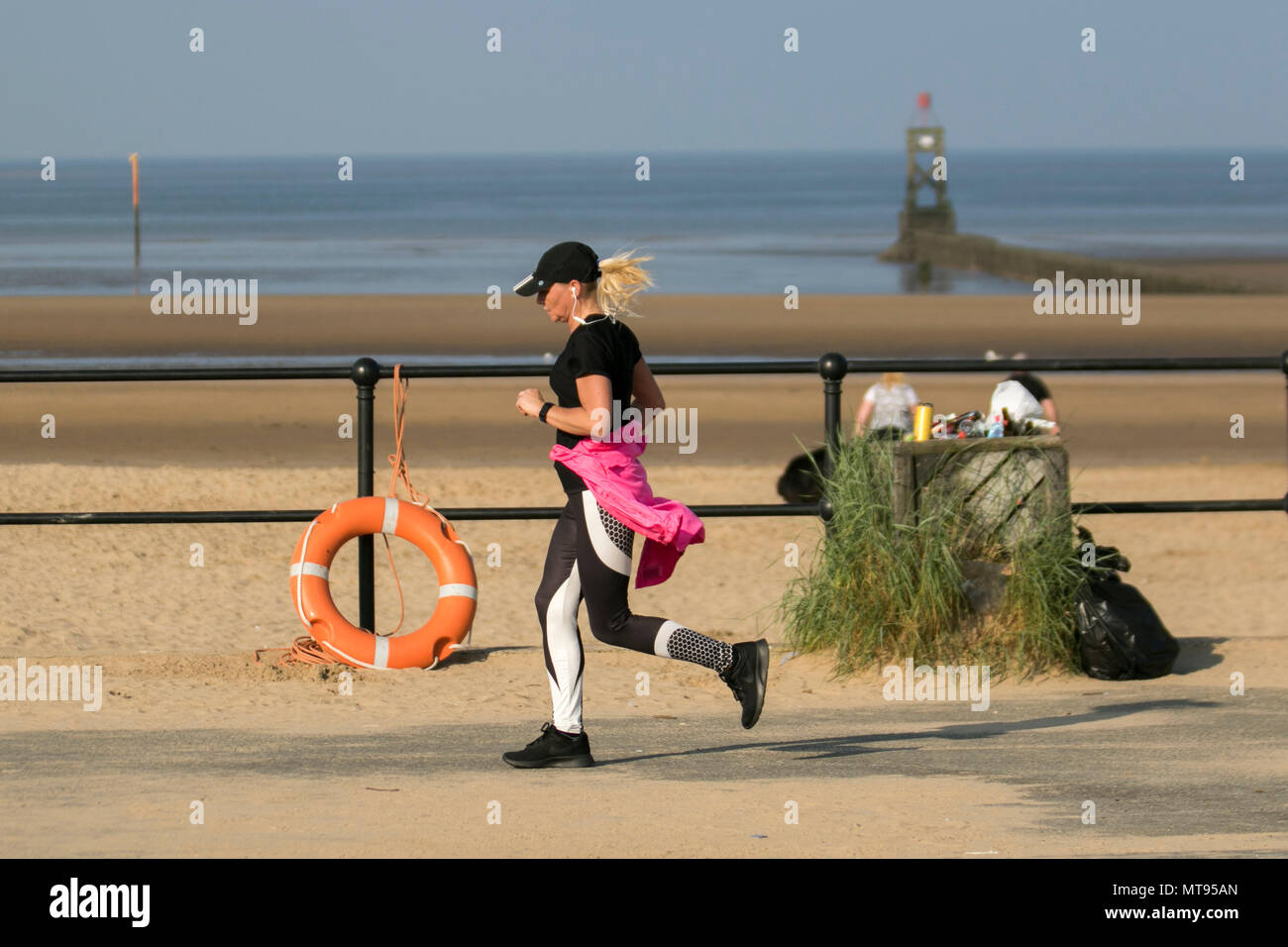 Donna che corre sul lungomare di Crosby, Liverpool. 29th maggio 2018. UK Meteo: Luminoso giorno estivo sulla costa nord-occidentale, mentre i residenti locali e i turisti si esercitano al mattino presto sul sentiero costiero e sulla spiaggia di Merseyside. La spiaggia è affollata con la lettiera Spring Bank Holiday con bidoni traboccanti e spazzatura che soffia nella brezza. Il Consiglio di Sefton containers chiaramente inadeguato per la quantità di rifiuti di plastica. Credit: MediaWorldImages/AlamyLiveNews. Foto Stock