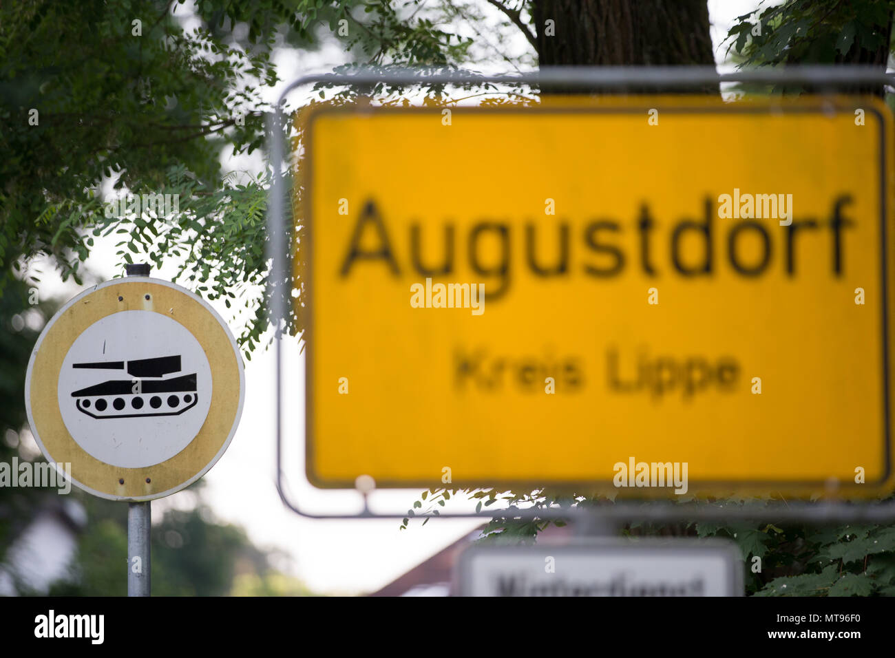 29 maggio 2018, Germania, Augustdorf: un segno a leggere 'Augustdorf'. Dietro di esso è un segno con un serbatoio. A causa della rotazione prevista di noi le forze militari in Europa orientale, noi veicoli militari sono la guida su autostrada federale A2, con una sosta presso la baracca militare dell'esercito tedesco (Generalfeldmarschall-Rommel-Kaserne). L'operazione 'Atlantic risolvere" con circa 300 veicoli è di essere completato entro la fine del mese. I trasporti militari potrebbero causare interruzioni temporanee del traffico. Foto: Friso Gentsch/dpa Foto Stock