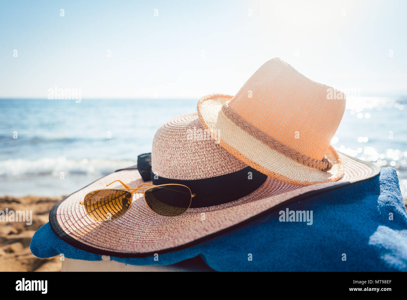 Cappello da sole e di occhiali sulla spiaggia con acqua Foto stock - Alamy
